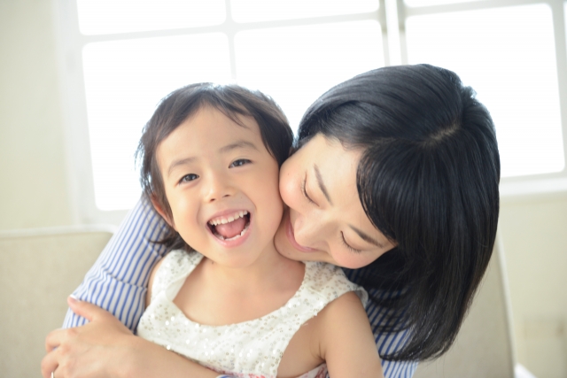 笑顔の小さな女の子とそれを優しく抱きしめる母親