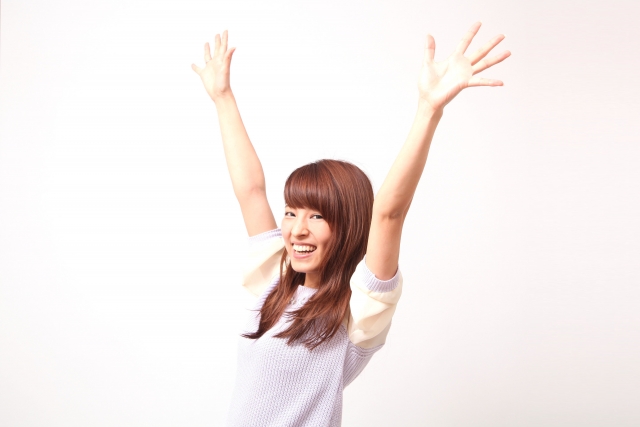 両手を上にあげて喜ぶ女性