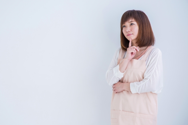 考え事をするエプロン姿の女性