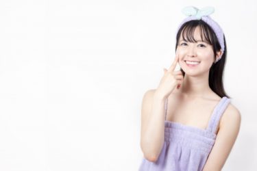頬に指先を押し当てる笑顔の女性