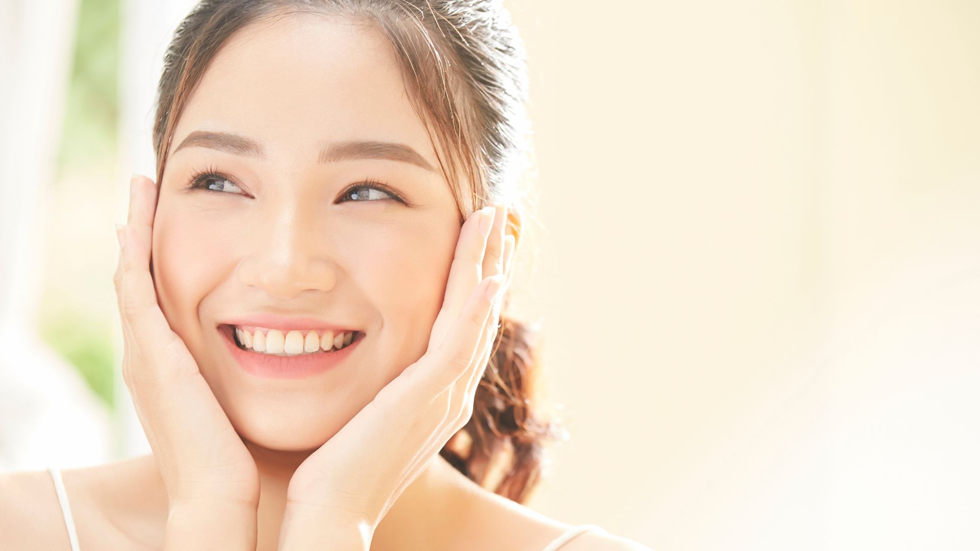 笑顔で両手を頬にあてている女性